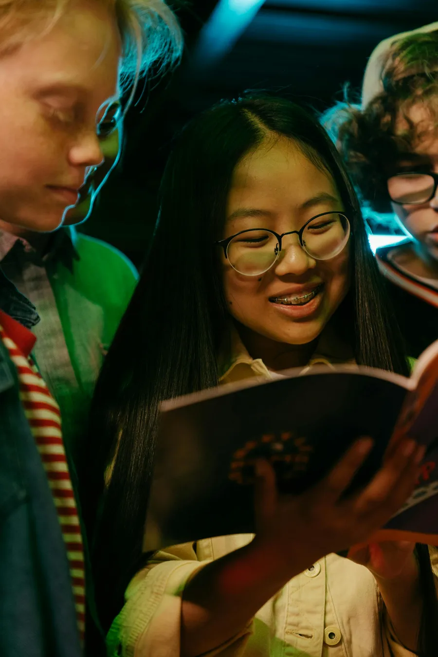 Three young people smiling as they read together